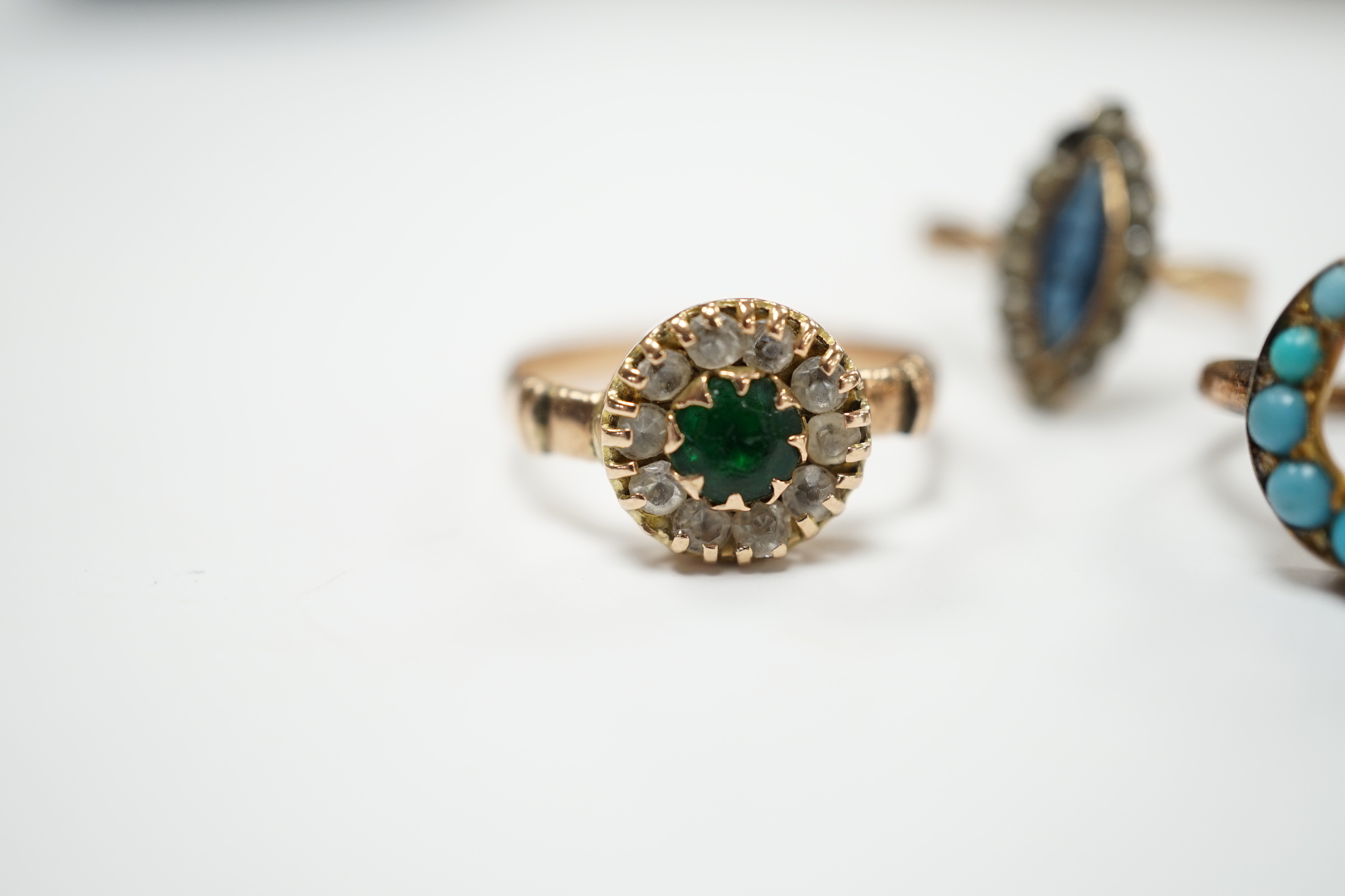 An early 20th century 9ct gold and two colour pastes set circular cluster ring, a 333 (8ct) ring and one other yellow metal and turquoise set horseshoe ring, gross weight 5.6 grams.